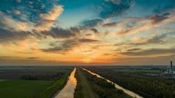 drone over two rivers at sunset featuring bright lit up sky.