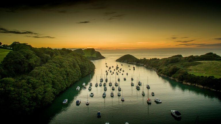 Watermouth Cove at sunset over water with small boats.
