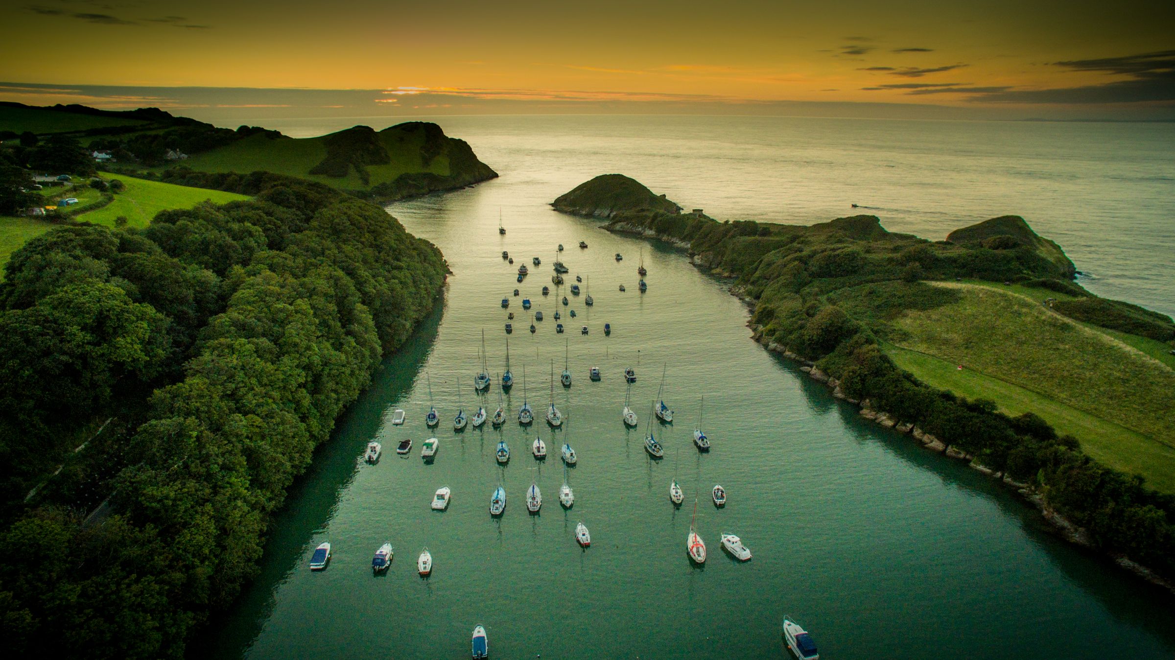 Watermouth Cove at sunset over water with small boats.