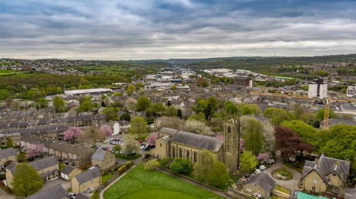 The town of Brighouse has a lovely parish church and within this image there are houses, shops , building sites and in the distance the M62 motorway.