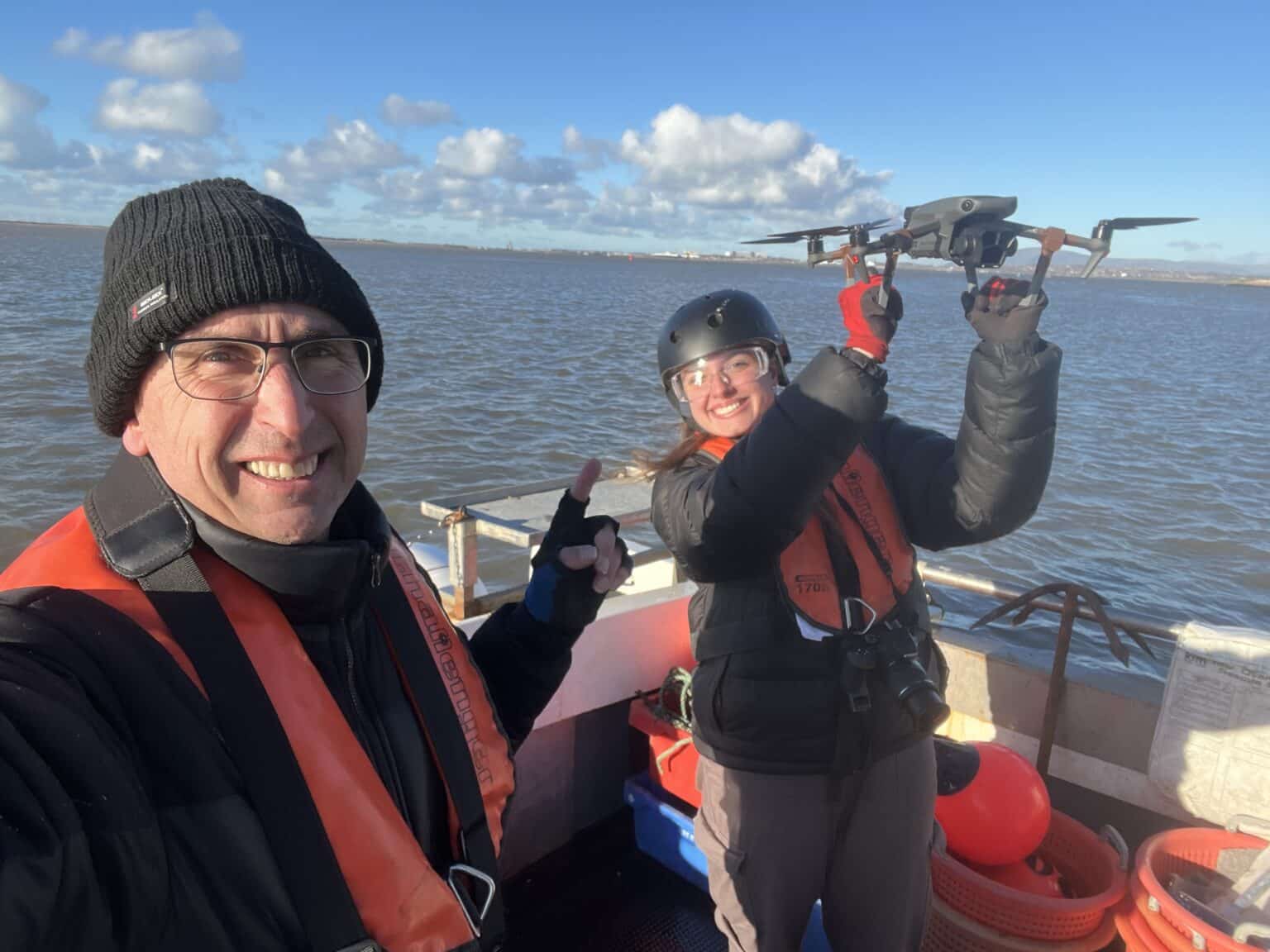 A crew member ready to hand catch the drone on a boat