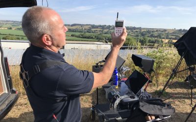 Darren Miller checking Radio Waves stood with the drone remote control, trees , grass and fields
