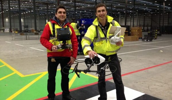 filming Indoors with a drone. Cameraman Ian Fearnley and Drone Pilot Phil Fearnley. Dressed in His Visibility safety clothing. Filming in a large warehouse