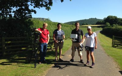 Multi drone crew team photo with crew at Daisybeck studios holding the Drone. country side with fields are all around whilst filmed in the summer